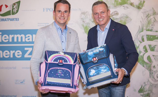 Foto zur Schultaschen-Aktion: FPÖ-Landesparteiobmann Mario Kunasek und FPÖ-Klubobmann Stefan Hermann verschenken Schultaschen an steirische „Taferlklassler“.